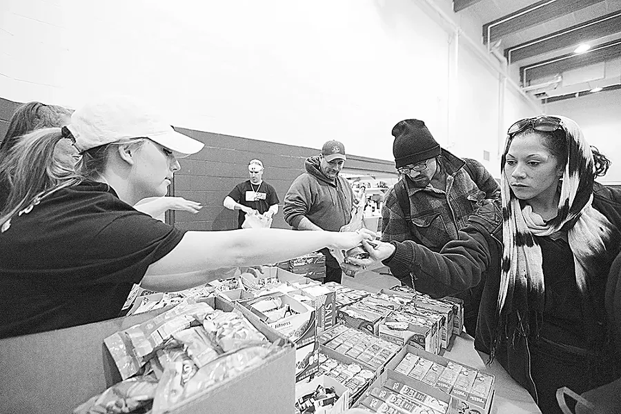 Volunteer Jody Jones, left, hands food items to Genesis Marcial, who has been homeless for 8 months, at the food bank during Homeless Connect, held at the Salvation Army. - YOUNG KWAK