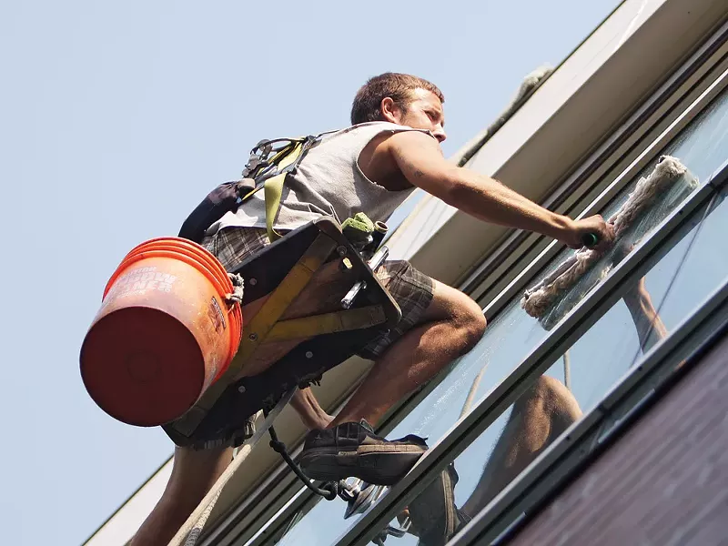 West Coast Window Cleaning employee John Peterson clings to the side of the Spokane Arena. - YOUNG KWAK