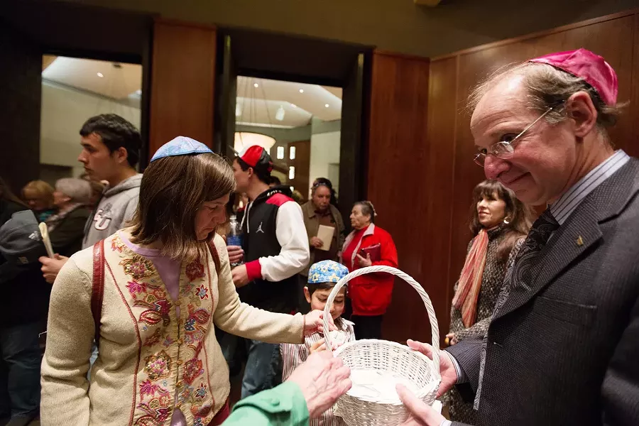 Yom HaShoah Planning Committee member Bill Bender, right, hands out pins to Juliet Barenti, left, and her 6-year-old son Jacob. The pins say "zachor," which translates to "remember." - YOUNG KWAK