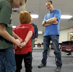 Lincoln Safran gets handcuffed by a fellow student as Officer Phillip Tremblay looks on.