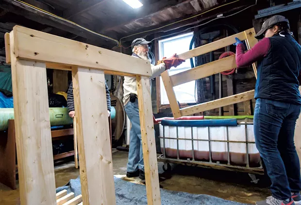 Volunteers prepare to dunk a headboard in a vat of homemade wood stain - GLENN RUSSELL