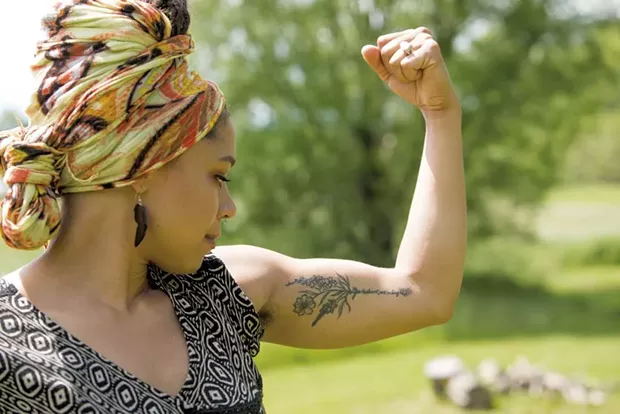 Kia'Rae flexes her tattoo, which reads "Life is short, art is long - CAT CUTILLO
