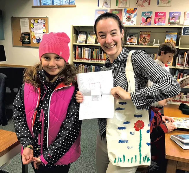 Mira gives a painted tote bag and note to our children's librarian
