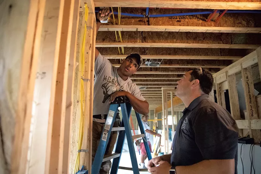 Essex High School senior Keshon Peters (left) and instructor Chris Welch discuss the measurements needed to cut ceiling drywall to fit around a corner - JAMES BUCK