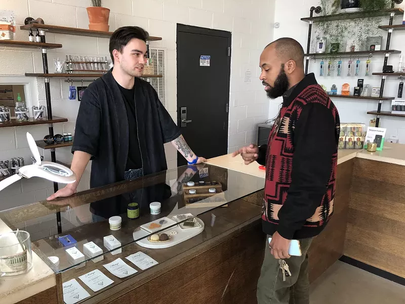 A budtender helps a customer at Detroit’s BotaniQ. - LEE DEVITO