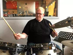 Jason Gittinger at a drum kit at his Detroit School of Rock and Pop Music. - PHOTO BY DUSTIN BLITCHOK