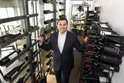Aaron Belen stands among the wine racks at Bistro 82. - PHOTO BY VAUGHN GURGANIAN
