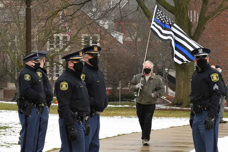 Man carrying a “blue line” flag signifying support for police on the lawn of the Michigan Capitol. - LESTER GRAHAM / SHUTTERSTOCK.COM