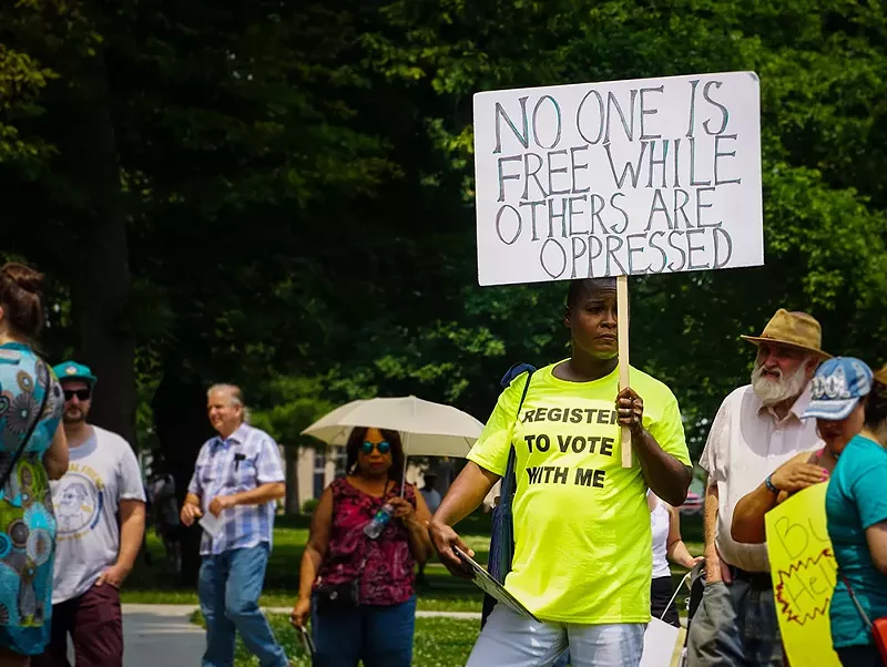 An activist in Detroit holds a protest sign that says 