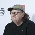 Flint native Michael Moore sprays 'Flint Water' near Snyder's office