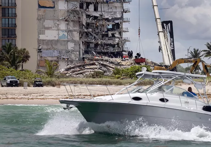 A boat passes off shore as members of the South Florida Urban Search and Rescue team look for possible survivors. - PHOTO BY JOE RAEDLE/GETTY