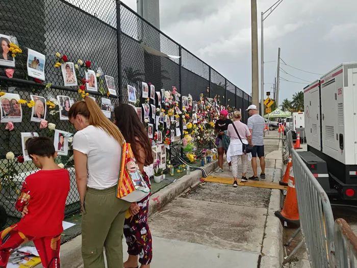 Visitors and residents of Surfside pay their respects to those lost in the Champlain Towers South Collapse at a memorial wall on Monday, June 28. - PHOTO BY JOSHUA CEBALLOS