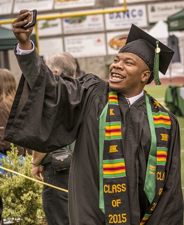 Journalism major Anthony Johnson takes a selfie as the 2015 candidates for graduation enter Redwood Bowl. - MARK LARSON