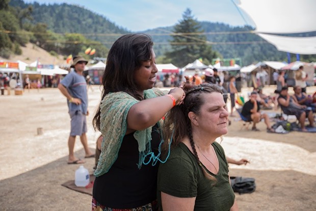 Jerusha Westlake works as a vendor braiding hair for her and her mother's business "Braids With Love" at the 30th annual Reggae On The River 2014, Friday Aug. 1. - ALEXANDER WOODARD