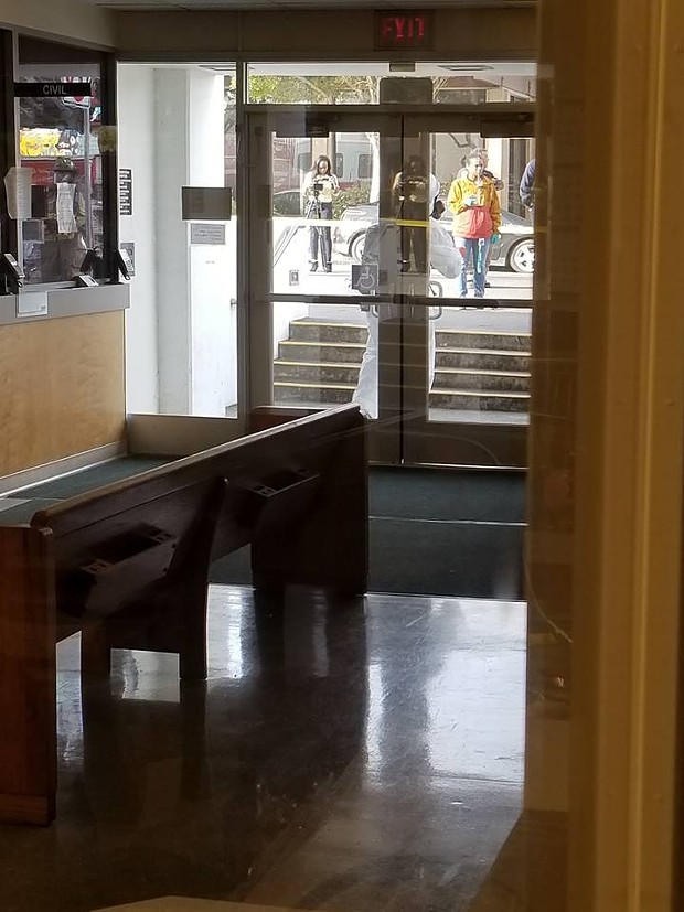 A Hazmat suit protects personnel outside of the Courthouse Clerk’s Lobby as seen from inside the lobby. - COURTESY OF MICHELLE BISHOP