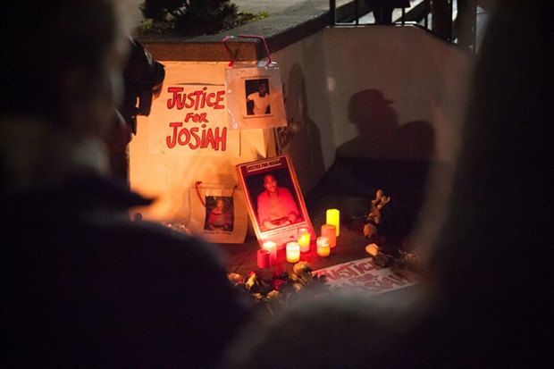 A Justice for Josiah sign and posters of Lawson illuminated by candlelight at the vigil. - MARK MCKENNA
