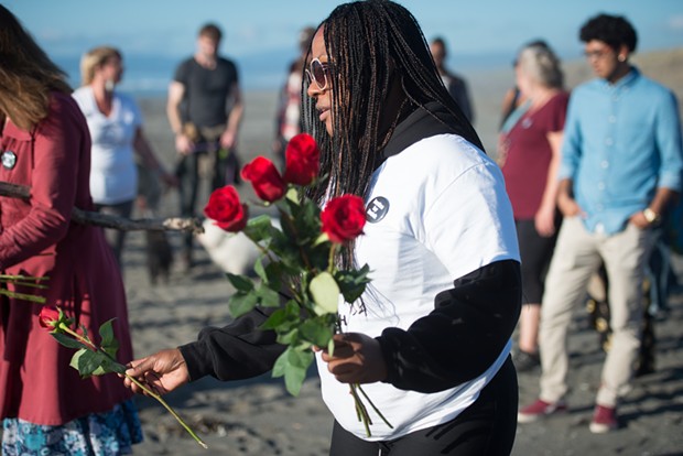 Charmaine Lawson places roses in two hearts drawn in the sand at a recent vigil held for her son. - MARK MCKENNA