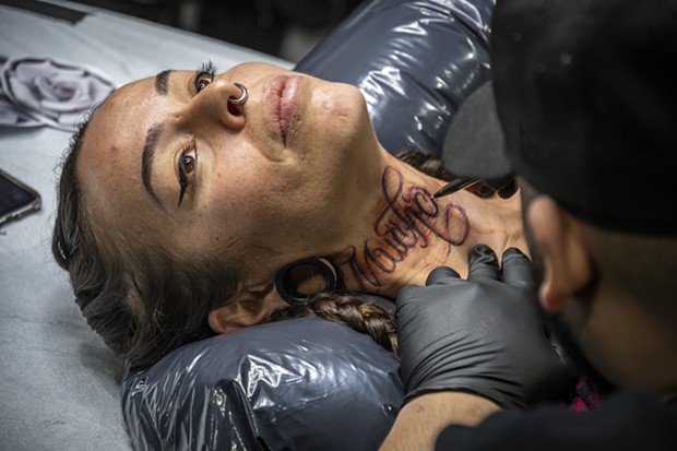 Tattoo artist David Chavera, of Local Boy Tattoo in San Antonio, Texas, preps a "Much Love" design in Spanish on the neck of Roxanne Reche, of Willow Creek. - PHOTO BY MARK LARSON