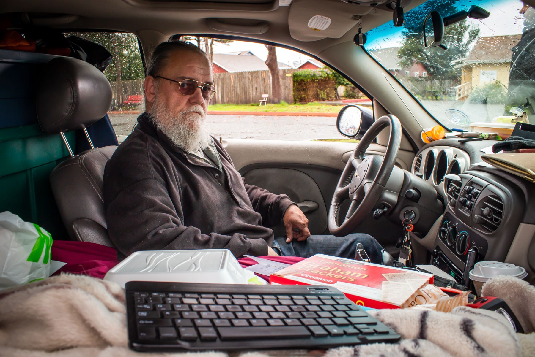 Robert Stretton inside his PT Cruiser in the parking lot of Sempervirens, with his wireless keyboard by his side and a prescription pill bottle on the dashboard. - PHOTO BY T.WILLIAM WALLIN