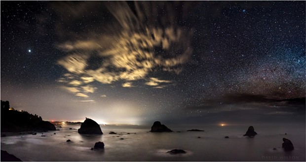 The rugged northern California coast is battered by a constant barrage of waves, their motion smoothed out in this 25-second exposure. Puffy clouds blowing by overhead were changed to streaks in the camera by their motion. Only the stars and rocks appeared to be still. - DAVID WILSON