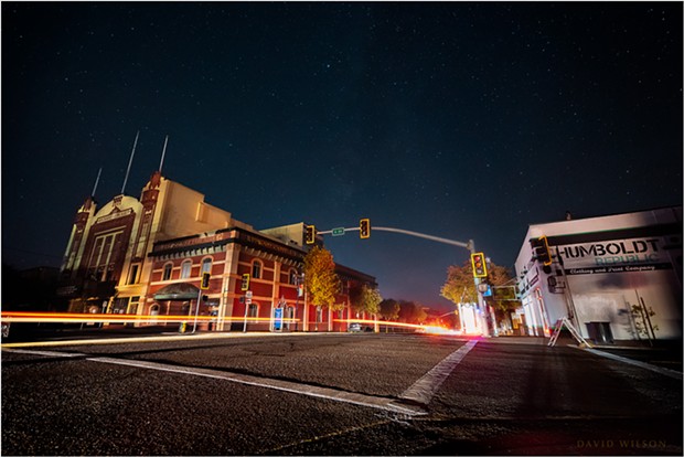 All city lights were out in Eureka, California, during PG&E's Public Safety Power Shutoff on October 27, 2019. The headlights of a few passing cars illuminated the scene, leaving trailing streaks from their taillights. 4th & G Streets, Eureka. - DAVID WILSON