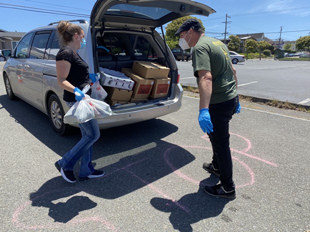 Volunteers load food into the trunk of a waiting car at a recent food distribution. - SUBMITTED
