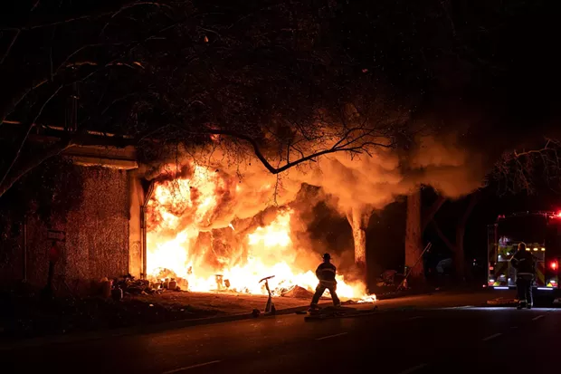 Sacramento firefighters respond to a fire at a homeless encampment under Highway 80 near 14th Street and X Street on Feb. 24, 2022. - PHOTO BY MIGUEL GUTIERREZ JR., CALMATTERS
