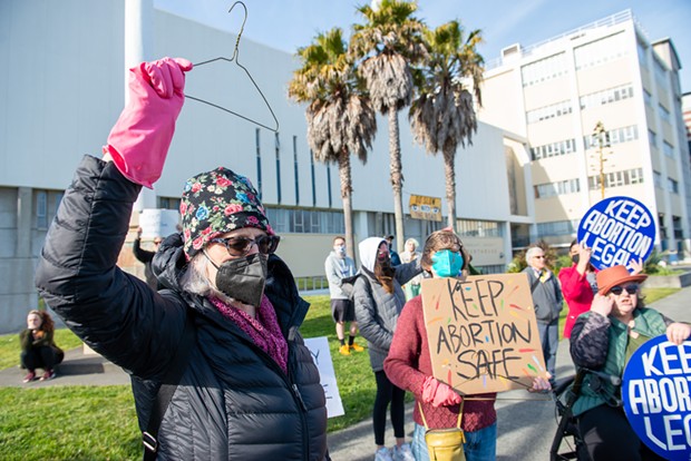 Erin Sullivan, wearing a pink glove and waving a coat hanger was one of dozens who turned out to support reproductive health at the courthouse on Tuesday. - PHOTO BY MARK MCKENNA