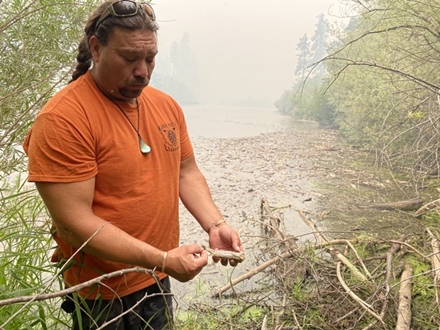 Kenneth Brink, of the Karuk Tribe, holds a dead fish on the bank of the Klamath River. - KARUK TRIBE