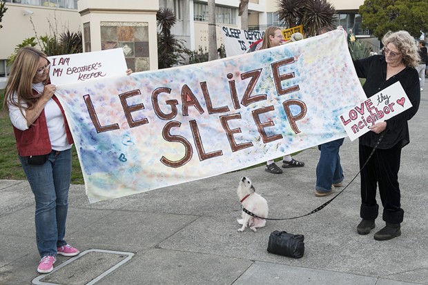 Carla Ritter, left, and Carlene "CC" Schultz, both of Fieldbrook, hold a banner supporting the decriminalization of sleeping in public. Schultz says she spent a year houseless in Humboldt County before getting a home. She said she had also been a "street mom" for eight to 10 years helping kids on the street and others when she had an RV. - MARK MCKENNA