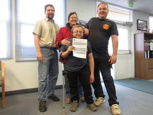 Three generations of growers, Rain on the Earth with her nephews Mark Switzer (far right) and grand-nephew Myles Moscato (center) pose with Wall as Moscato proudly holds the receipt for his application, the first submitted in the county. - LINDA STANSBERRY