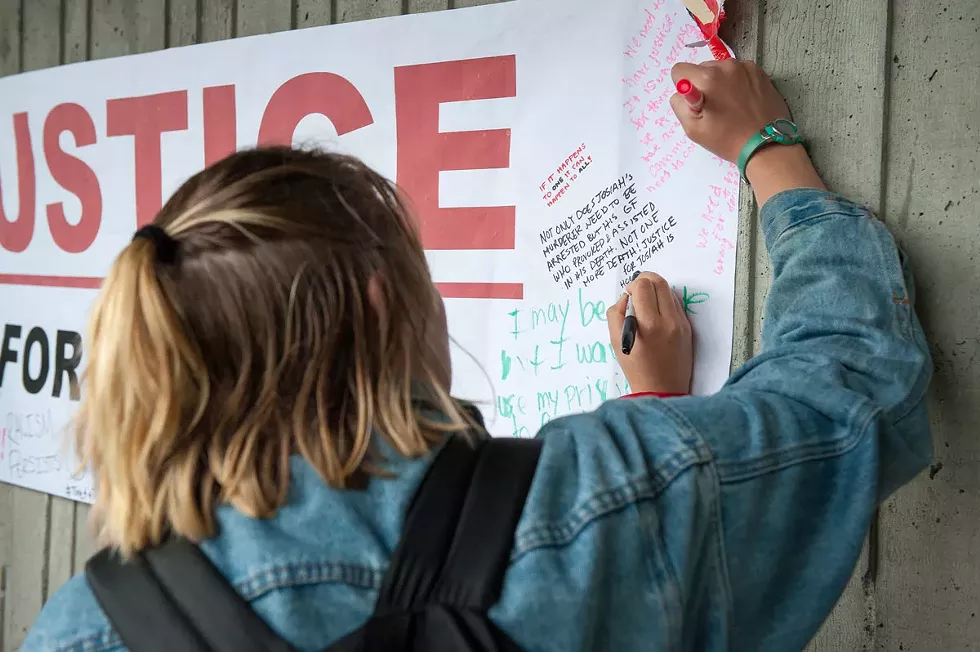 A student signs the "Justice for Josiah" banner. - PHOTO BY MARK MCKENNA