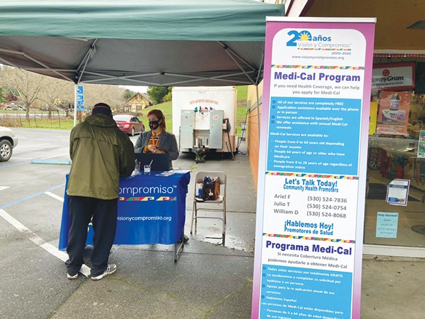 Ariel Fishkin, Visi&oacute;n y Compromiso community promotor, helping someone apply for Medi-Cal while outreaching.