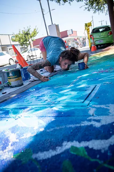 Ashley Rose blows glitter into the paint of her work titled "Complement in Chaos." - PHOTO BY MARK MCKENNA