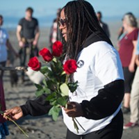 Charmaine Lawson places roses in two hearts drawn in the sand at a recent vigil held for her son.