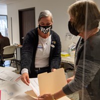 Poll worker Kristen Porter, left, places a ballot in a folder held by Julie Fulkerson at the Eureka Pentecostal Church on Hoover Street. Porter has worked several elections while Fulkerson was working her first at the polls.