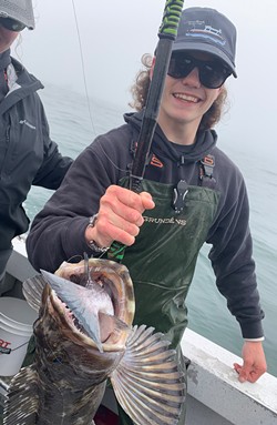 PHOTO COURTESY OF BROOKINGS FISHING CHARTERS - Eric Howard, a deckhand for Brookings Fishing Charters, holds a lingcod caught last week aboard the Miss Brooke while fishing out of Brookings, Oregon. The lingcod latched onto a blue rockfish.