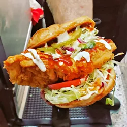 PICKLE-BRINED The Grinning Bear dishes out fried chicken with a spicy kick in the Firebird Sandi, which comes with honey hot sauce, ranch, barbecue sauce, lettuce, tomato, homemade pickles, apple cole slaw, and pepper jack cheese on a Hawaiian roll. - PHOTOS COURTESY OF BRENEN BONETTI
