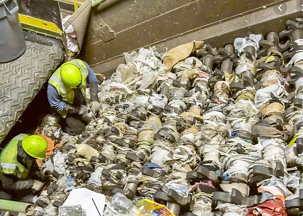 STUCK ON PLASTIC Workers attempt to remove plastic bags from the machinery at a recycling facility. - PHOTO COURTESY OF PATTI TOEWS