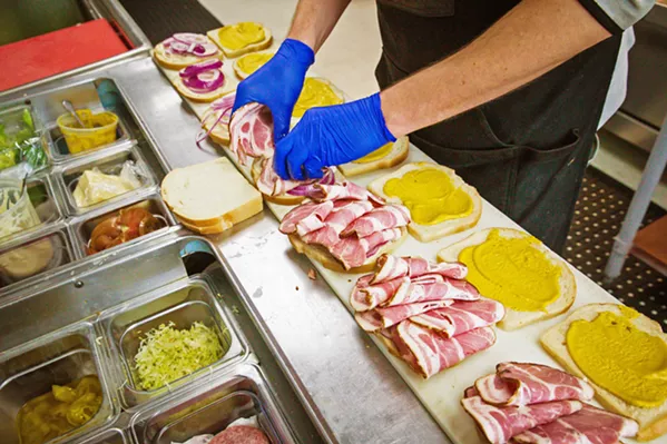 EAT THE PORK Kitchen manager Evan Martz preps some cold pork shoulder sandwiches for the lunch rush. - PHOTOS BY JAYSON MELLOM