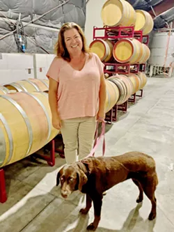 BEHIND THE SCENES Administrator and e-commerce sales director Alyssa Ball and her blind 9-year-old chocolate Labrador, Scout, are an inseparable team at Ragtag's wine production facility. - PHOTO BY CHERISH WHYTE