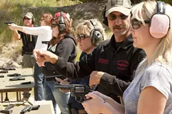 LINE UP : Instructors John Marrs and John Odom teach safe gun techniques to (l-r) Suzanne Russell, Maeva Considine, Kelly Fontes, and Stephanie Ross. - PHOTO BY STEVE E MILLER