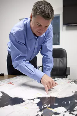 IN OUR OWN BACKYARD : Tim Williams, president of San Luis Obispo-based telecommunications firm Digital West, showed off a map of trans-Pacific fiber-optic cables on the West Coast—a cluster of which runs from Asia straight to the shores of Grover Beach. - PHOTO BY STEVE E. MILLER