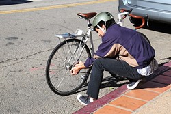 GOLD STATUS:  A Cal Poly student fixes his bike in Downtown SLO. The city was recently elevated from Silver to Gold status as a bike-friendly city by the League of American Bicyclists. The promotion coincides with news that the SLO Police Department received a $190,000 state grant to prevent bike and pedestrian fatalities. - PHOTO BY DYLAN HONEA-BAUMANN