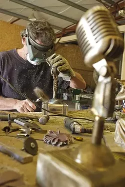 Baxter sands down one of the awards to prepare it for the patina. - PHOTO BY STEVE E. MILLER