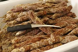 26:: A tray of Salsiccia Calbrese, which specifically is made with paprika from Calabrese. These salamis will be peeled from their casing and are commonly kept in a jar with oil.