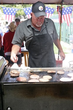 FLIPPIN&rsquo; BURGERS! :  Ken, an Elks Lodge volunteer, kept the burgers coming all afternoon during the July 4th pool party. - PHOTOS BY GLEN STARKEY