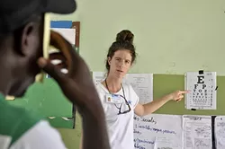 TESTING: Peace Corps volunteer Claire Dal Nogare points to the letters of vision test on the wall in a makeshift medical clinic in Sabana Larga. Dal Nogare and four other Peace Corps volunteers based in the Dominican Republic helped translate in Spanish and English during the latter part of the week. - PHOTO BY CAMILLIA LANHAM