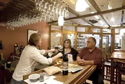 FOR A GOOD TIME : Rick Cronkhite recently poured some vino for Ralph and Dolores Vasquez at the newly opened Central Coast wines. - PHOTO BY STEVE E. MILLER