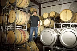 MORE FUN THAN A BARREL OF MONKEYS: Ryan Deovlet, winemaker, stands amongst some of his aging barrels at his Deovlet winemaking facility in San Luis Obispo. - PHOTO BY STEVE E. MILLER